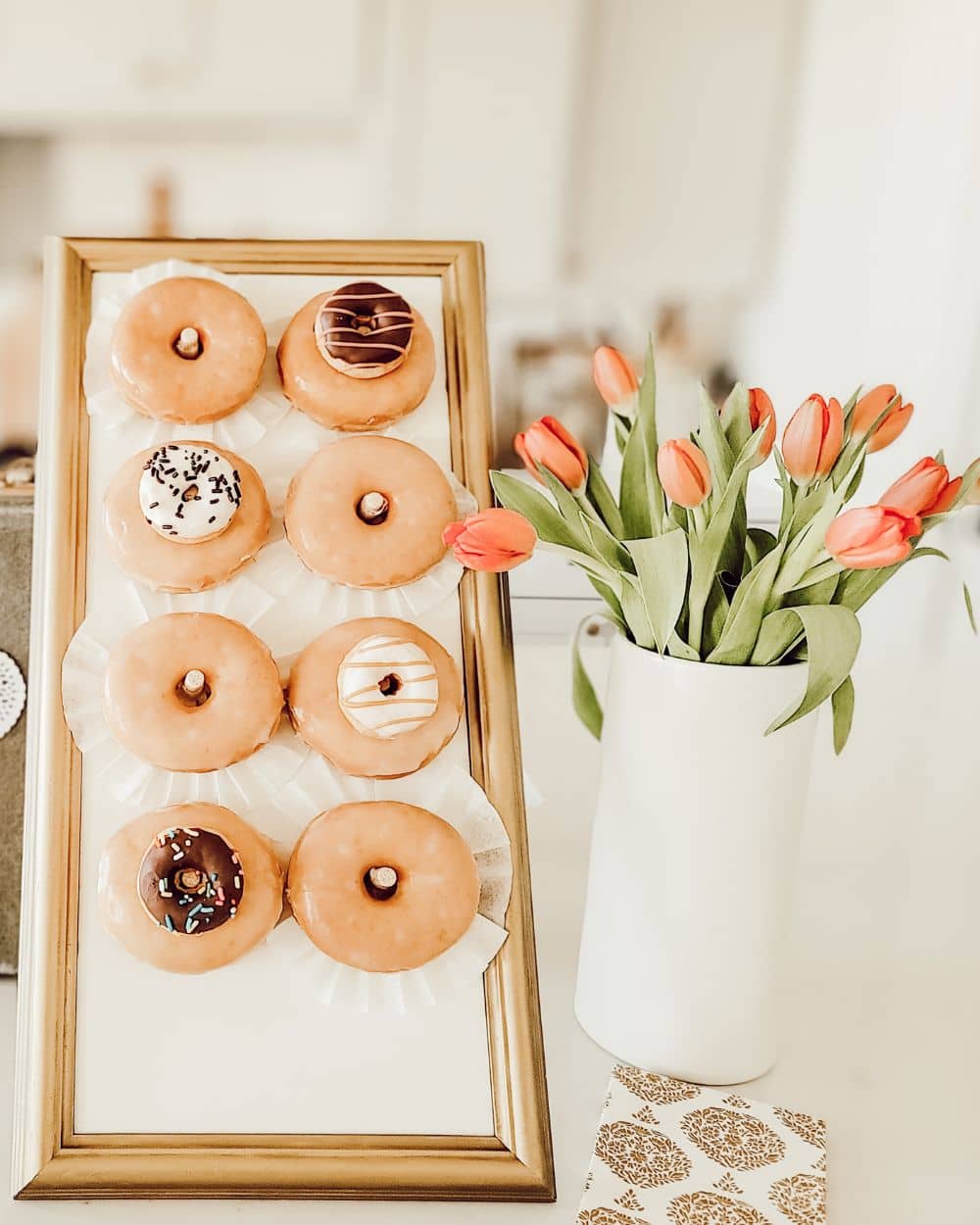 A DIY donut board in a vintage frame with a vase of tulips