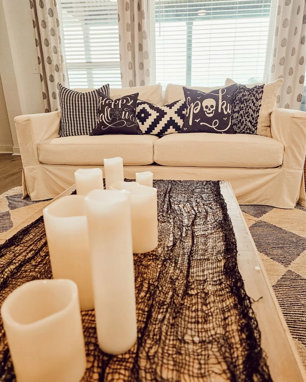 coffee table with candle centerpiece and Halloween pillows on sofa